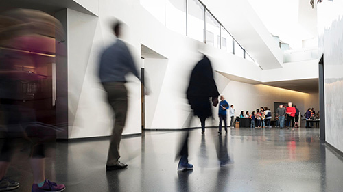 Blurry individuals walking through Bloch Lobby